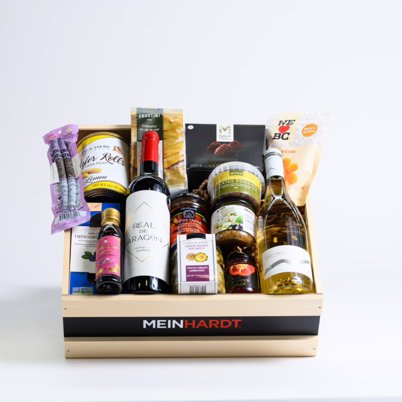 Snacks and Treats packed in a wooden crate with two wines in the front. The wooden crate is faded Beige color with a black strip and has Meinhardt written on it.