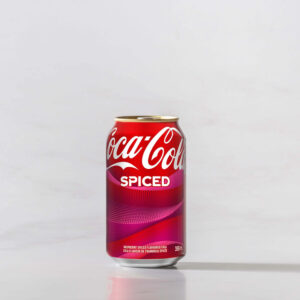 A can of Spiced Coke original on a table with a shadow to the right. Theme white marble.