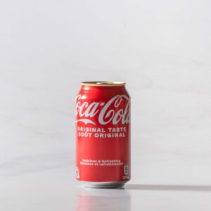 A can of Coke original on a table with a shadow to the right. Theme white marble.
